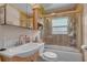 Bathroom with a white vanity, toilet, and a tiled shower-tub combo with glass door at 3106 E Diana St, Tampa, FL 33610