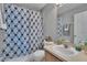 Well-lit bathroom features a patterned shower curtain and vanity with a decorative mirror at 3455 Castle Stone Ct, Valrico, FL 33594