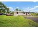 View of home from backyard, featuring a wood deck, green lawn, and cloudy blue skies at 37732 Cecil Ln, Zephyrhills, FL 33542