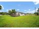 Backyard view featuring a green lawn, wood deck, and the home's exterior with blue skies at 37732 Cecil Ln, Zephyrhills, FL 33542