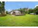 Exterior view of the home from the backyard showing green lawn and wood deck at 37732 Cecil Ln, Zephyrhills, FL 33542