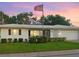 Charming single-story home with lush green lawn and mature landscaping displayed with a picturesque American flag at 4076 Mainlands N Blvd, Pinellas Park, FL 33782