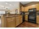 Kitchen with granite countertops, wood cabinets, black appliances, and an open view to the living area at 4207 S Dale Mabry Hwy # 8304, Tampa, FL 33611
