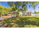 Well-maintained front yard with a charming home, lush lawn, mature trees, and a white fence at 428 Klosterman W Rd, Palm Harbor, FL 34683