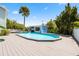 Inviting backyard pool area with spacious wooden deck, palm tree, and a blue pool house, perfect for outdoor relaxation at 428 Klosterman W Rd, Palm Harbor, FL 34683