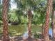 Scenic pond view, lined with stately palms and lush foliage, creates a tranquil tropical escape at 474 Hinton St, Port Charlotte, FL 33954