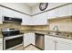 Kitchen featuring white cabinets, stainless steel appliances, and a tiled backsplash and floor at 504 S Armenia Ave # 1329B, Tampa, FL 33609
