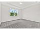 Spacious bedroom featuring a large window, neutral walls, and plush gray carpeting at 6019 Shorebird Br, Land O Lakes, FL 34638
