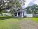Quaint single-story home featuring a covered front porch, fenced yard, and mature trees for added privacy at 606 N Merrin St, Plant City, FL 33563