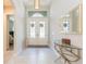 Bright foyer with decorative glass doors, complemented by a glass table, mirror, and neutral decor at 6331 Voyagers Pl, Apollo Beach, FL 33572
