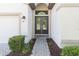 Inviting entryway featuring double doors with glass inserts, enhanced by manicured bushes and a brick walkway at 6331 Voyagers Pl, Apollo Beach, FL 33572