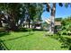 Spacious backyard featuring mature trees, lush green lawn, and partial fencing, creating a tranquil outdoor setting at 7684 Oakhurst Rd, Seminole, FL 33776