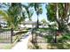 Charming home featuring a manicured lawn, mature trees, and black metal decorative fencing at 7684 Oakhurst Rd, Seminole, FL 33776