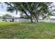 A view of the exterior of the home with a lush, green lawn, a white fence and mature trees at 1008 Shangri La Dr, Seffner, FL 33584