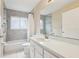A clean, well-lit bathroom with a shower-tub combination, white vanity, and gray tile at 10304 Rainbow Oaks Dr, Hudson, FL 34667