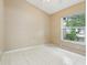 A simplistic bedroom features tile floors, neutral colored walls and a large window allowing for plenty of natural light at 10304 Rainbow Oaks Dr, Hudson, FL 34667