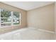 A simplistic bedroom features tile floors, neutral colored walls and a large window allowing for plenty of natural light at 10304 Rainbow Oaks Dr, Hudson, FL 34667
