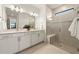 Modern bathroom features double vanity, large mirror, and glass-enclosed shower with bench at 10463 Abaco Falls Dr, Englewood, FL 34223