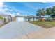 This single-story home features a long driveway, attached garage, and mature palm tree at 1051 Pert Ln, Holiday, FL 34691