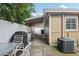 A backyard with concrete slabs, an AC unit, grill, and chairs under a covered awning at 109 Emerald Ln, Largo, FL 33771