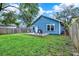 This backyard features a blue house, lush green grass, an outdoor seating area, and a privacy fence at 111 E Jean St, Tampa, FL 33604