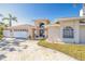 Front exterior of home featuring a paver driveway, lush lawn and a two car garage at 11160 8Th E St, Treasure Island, FL 33706