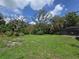 A spacious backyard features lush green grass, mature trees, and a screened-in pool area at 11307 Sandpine Rd, Riverview, FL 33569