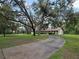 A long driveway shaded by mature trees leads to a charming house with green lawn at 11307 Sandpine Rd, Riverview, FL 33569