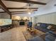 Comfortable living room featuring a stone fireplace, exposed beams, and a plush blue sectional at 11307 Sandpine Rd, Riverview, FL 33569
