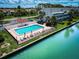 Community pool featuring patio seating, umbrellas, and lounge chairs beside a canal and low-rise condos at 12132 Capri S Cir, Treasure Island, FL 33706