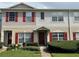 Inviting two-story townhome with red shutters, manicured lawn and a neatly landscaped front yard at 15733 Stable Run Dr, Spring Hill, FL 34610