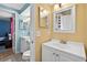 Bright bathroom featuring white cabinets, toilet, sink, and gold accents, with yellow and blue walls at 15925 Marshfield Dr, Tampa, FL 33624