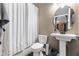 Well-lit bathroom featuring a toilet, pedestal sink, and a shower with a curtain at 165 Mobbly Bay Dr, Oldsmar, FL 34677