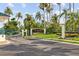 Community entrance featuring an elegant sign, lush landscaping, a secure gate, and swaying palm trees at 165 Mobbly Bay Dr, Oldsmar, FL 34677