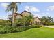 Beautifully landscaped home with a terracotta roof and a three-car garage with mature trees at 165 Mobbly Bay Dr, Oldsmar, FL 34677