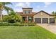 Charming, one-story home boasts a terracotta roof, three-car garage, and lush landscaping at 165 Mobbly Bay Dr, Oldsmar, FL 34677