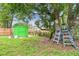 Green shed and ladders in a shady backyard with a large tree, offering storage and maintenance solutions at 1711 W Followthru Dr, Tampa, FL 33612
