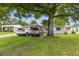 Exterior of home, shaded front yard, driveway with two cars at 1711 W Followthru Dr, Tampa, FL 33612