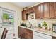 Cozy kitchen featuring stainless steel sink, warm wooden cabinets, and a door with a view of the pool at 1711 W Followthru Dr, Tampa, FL 33612