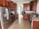 Spacious kitchen featuring tile floors, stainless steel appliances, rich brown cabinets, and granite countertops at 1753 Open Field Loop, Brandon, FL 33510