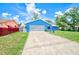 Charming single-story home features a blue exterior, a well-manicured front yard, and a concrete driveway at 2063 De Carlo Ave, Spring Hill, FL 34608