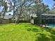 Expansive backyard with lush green lawn, screened-in pool, and mature trees at 2102 Doefield Ct, Valrico, FL 33596