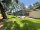 View of a screened-in pool area surrounded by green lawn and mature trees, offering a private outdoor space at 2102 Doefield Ct, Valrico, FL 33596