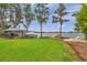 Picturesque backyard with lush green lawn, gazebo, boat, and lakeside relaxation area with chairs at 21906 Shamu Dr, Land O Lakes, FL 34639