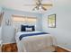 Light blue bedroom featuring a ceiling fan, window, surf art, and a queen bed with blue accents at 21906 Shamu Dr, Land O Lakes, FL 34639
