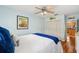 Bedroom with light blue walls, wood-look flooring, ceiling fan, and a view of the kitchen at 21906 Shamu Dr, Land O Lakes, FL 34639