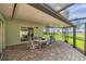 Cozy outdoor dining on a screened-in brick patio, offering picturesque views of the lush backyard and lake at 21906 Shamu Dr, Land O Lakes, FL 34639