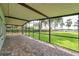 Large screened-in porch with brick flooring and serene views of the lush backyard and lake at 21906 Shamu Dr, Land O Lakes, FL 34639