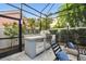 Outdoor built-in stainless grill and lounge chairs in screened-in lanai at 2604 W Jetton Ave, Tampa, FL 33629