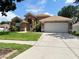 Exterior shot of a single-Gathering home with manicured lawn, mature landscaping, and a paved driveway leading to a garage at 28826 Windover St, Wesley Chapel, FL 33545